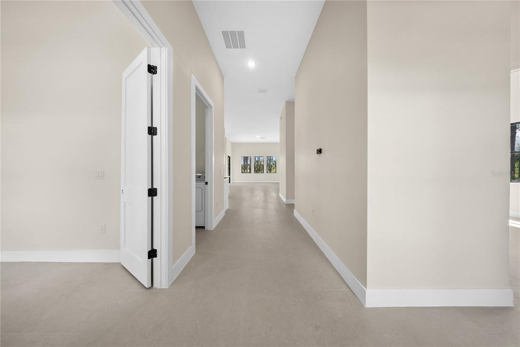 A hallway with light-colored tile flooring leads toward a room with three windows — 372 MATSON LANE, PORT CHARLOTTE, FL