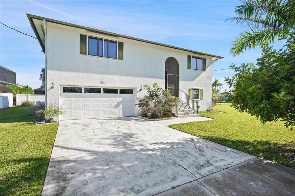 A two-story house with a white exterior, a two-car garage, and a front staircase — 103 TAHITI CIRCLE, NAPLES, FL