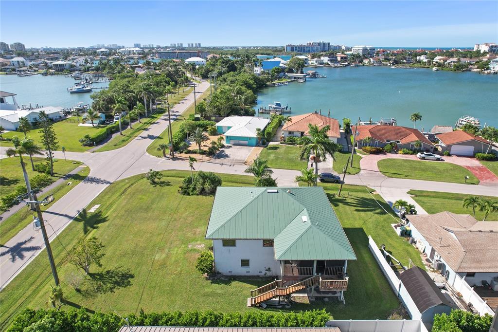An aerial view shows a house with a green metal roof near a coastal waterway — 103 TAHITI CIRCLE, NAPLES, FL