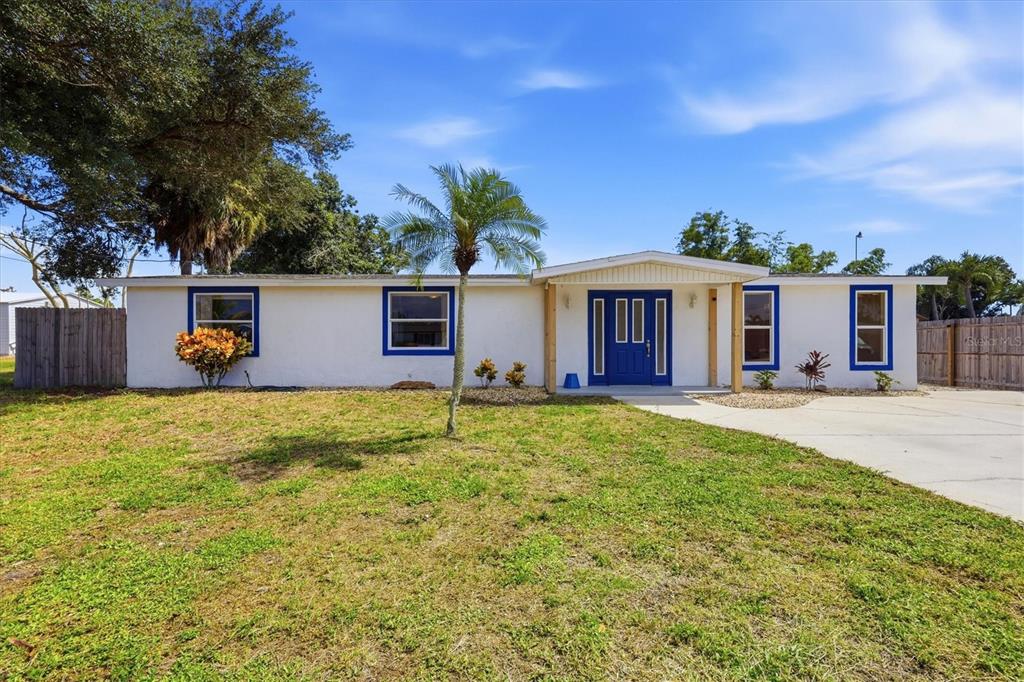 A single-story white house with blue trim and a blue front door sits on grass — 1157 SOUTH LANE, ENGLEWOOD, FL