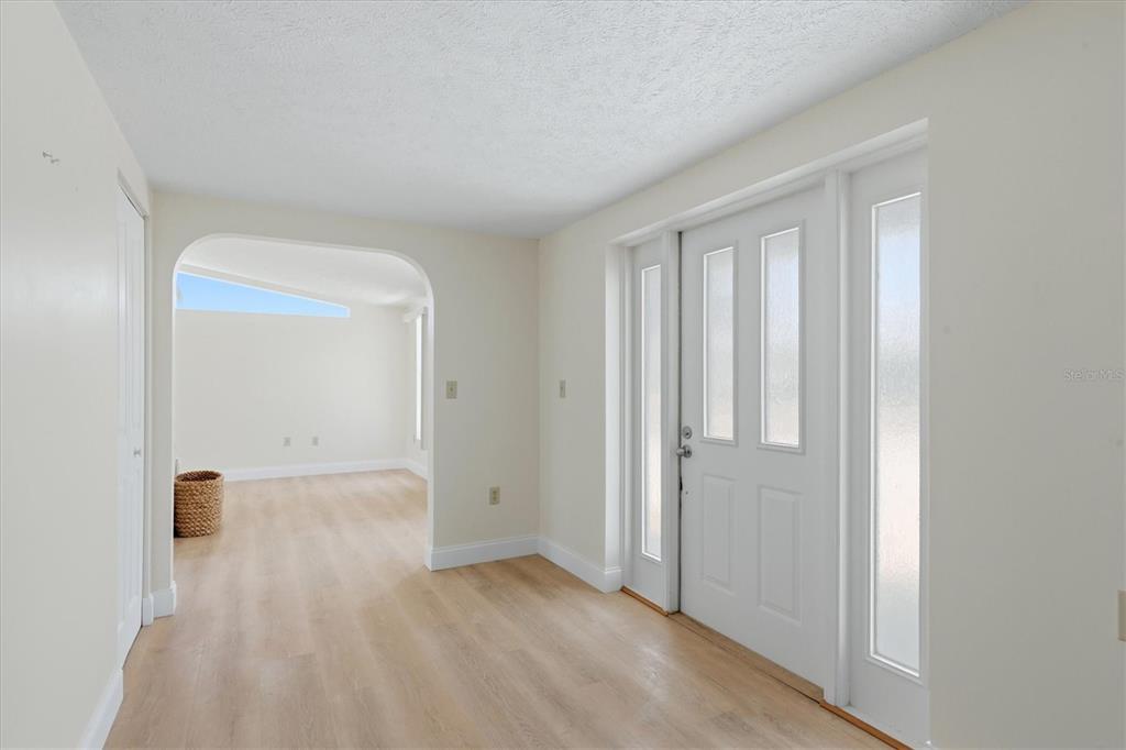 An entryway with light wood flooring, white walls, and a white front door — 1157 SOUTH LANE, ENGLEWOOD, FL