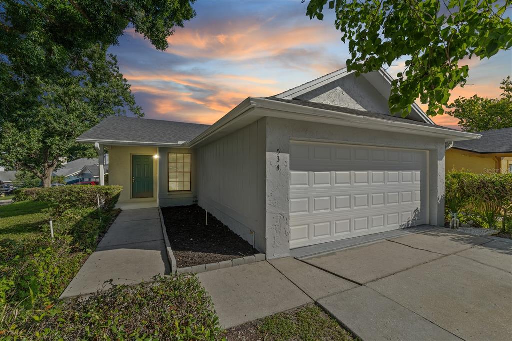 A single-story house with a white garage, a green front door, and a concrete walkway — 534 LAKE DEXTER BOULEVARD, WINTER HAVEN, FL