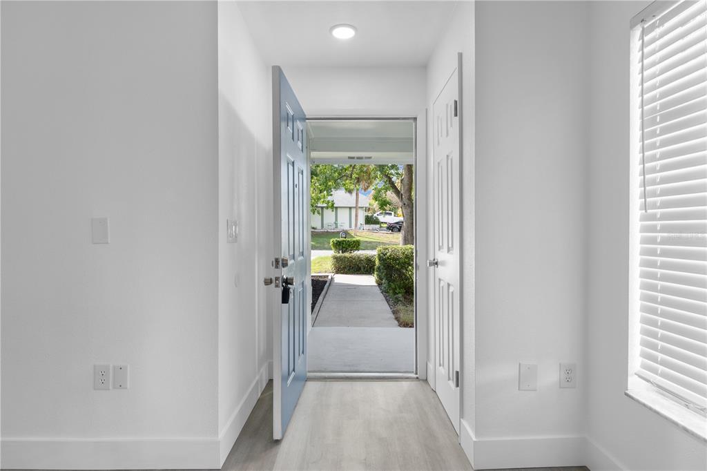 An entryway with light wood-look flooring, white walls, and an open blue front door — 534 LAKE DEXTER BOULEVARD, WINTER HAVEN, FL