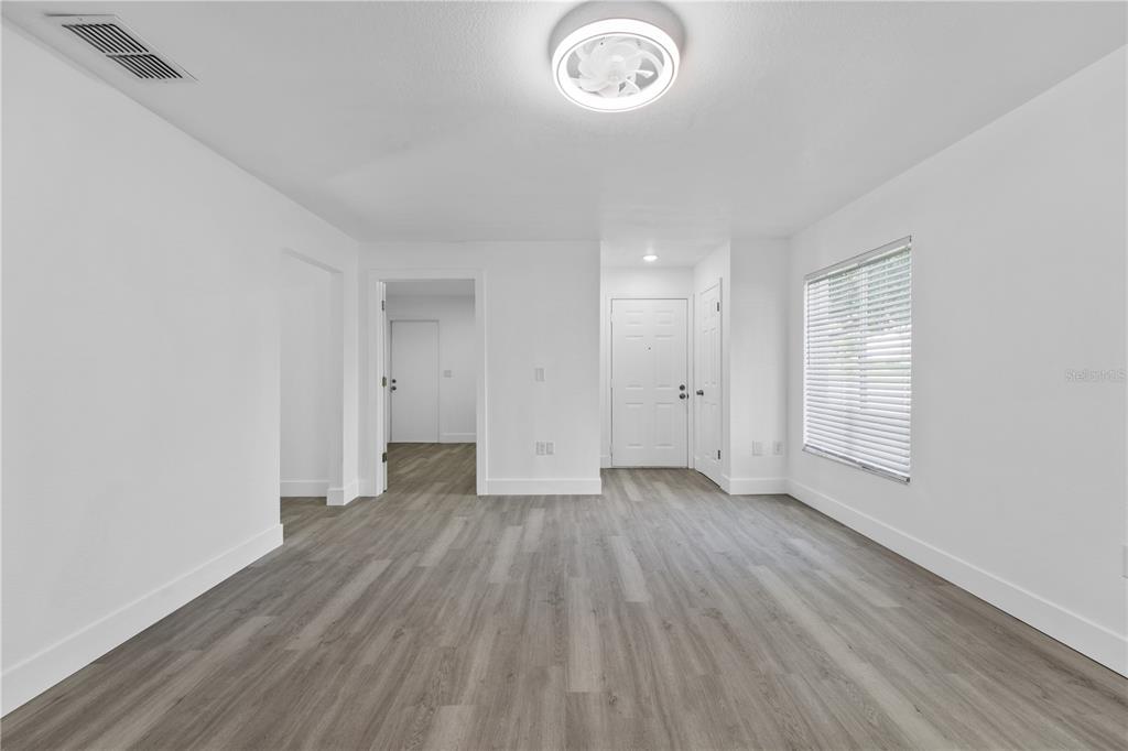 An empty room with white walls, gray wood-look flooring, a ceiling fan, and a front door — 534 LAKE DEXTER BOULEVARD, WINTER HAVEN, FL