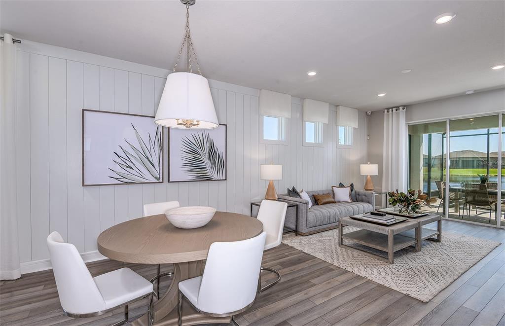 A bright open-concept living and dining area features white vertical wall paneling and wood flooring — 14753 SUNLIT CIRCLE, PARRISH, FL