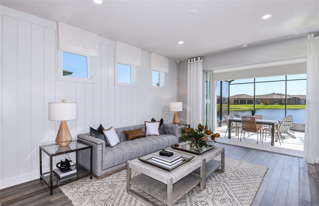 A living room with vertical white paneling, a gray sofa, and sliding doors to a patio — 14753 SUNLIT CIRCLE, PARRISH, FL