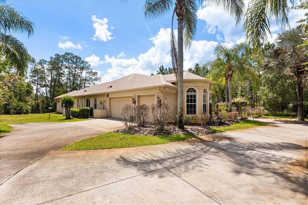A beige house with a two-car garage and a large concrete driveway surrounded by trees — 420 VALLEY STREAM DRIVE, GENEVA, FL