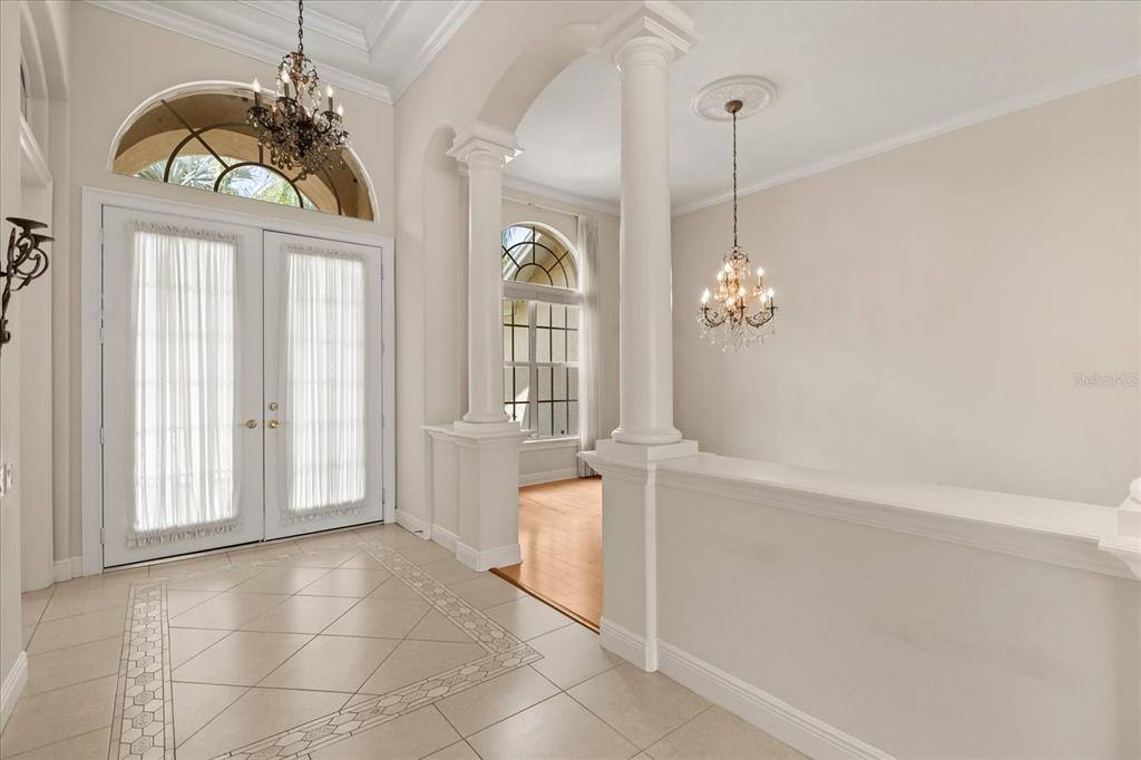 An entryway features tile flooring, a double front door, two chandeliers, and decorative columns — 420 VALLEY STREAM DRIVE, GENEVA, FL