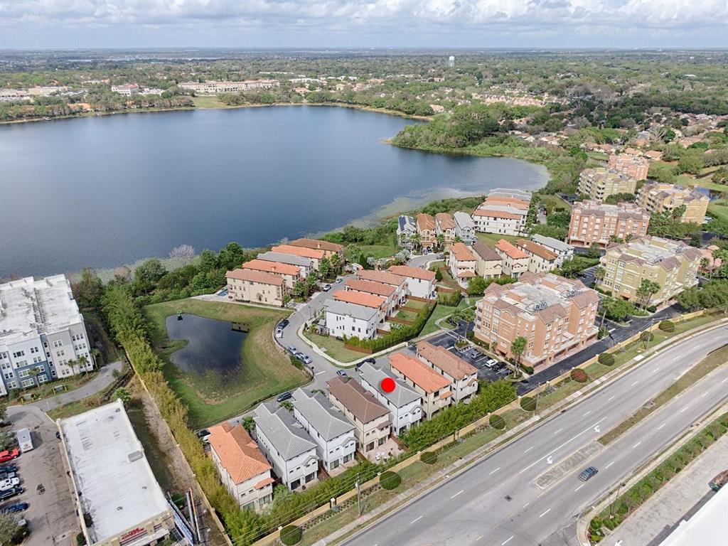An aerial view shows a row of townhomes with a red dot marking one unit — 7661 TOSCANA BOULEVARD, ORLANDO, FL