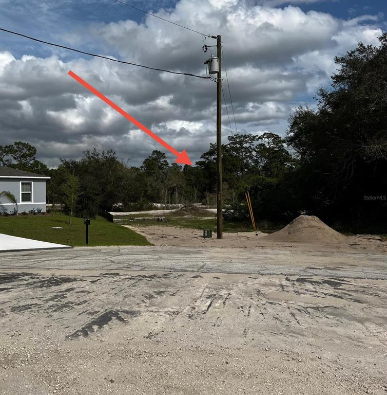 A vacant, sandy residential lot features a utility pole and a pile of dirt — 410 ASHBURY WAY, KISSIMMEE, FL