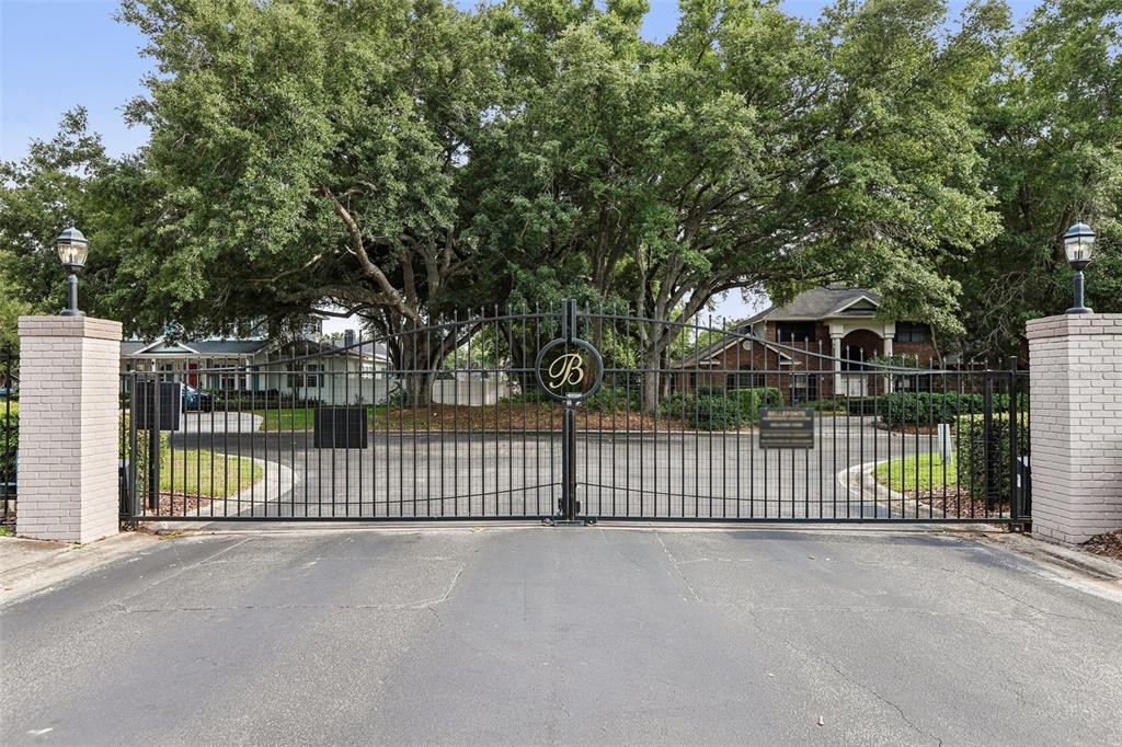A black metal gate with a letter B emblem stands between two brick pillars — 1012 MORFIELD LANE, BRANDON, FL