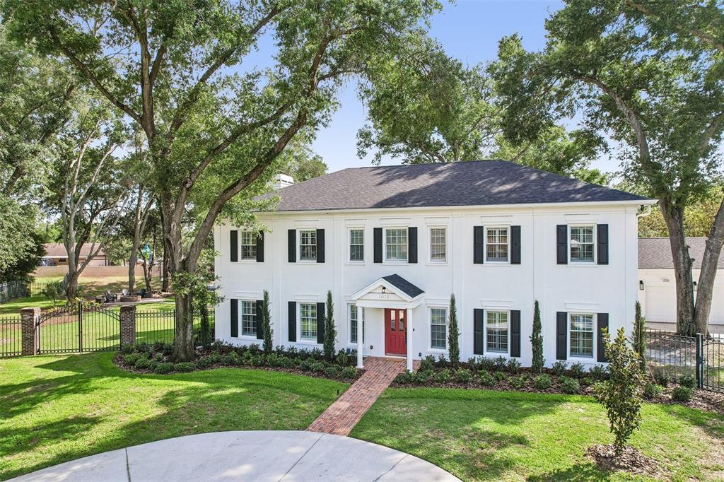 A two-story white house with black shutters and a red front door sits on a lawn — 1012 MORFIELD LANE, BRANDON, FL