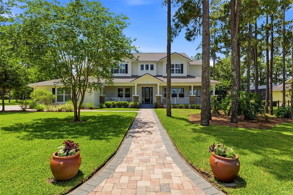 A two-story house with a paved walkway, front porch, and tall pine trees in the yard — 5251 SUMMIT VIEW DRIVE, BROOKSVILLE, FL