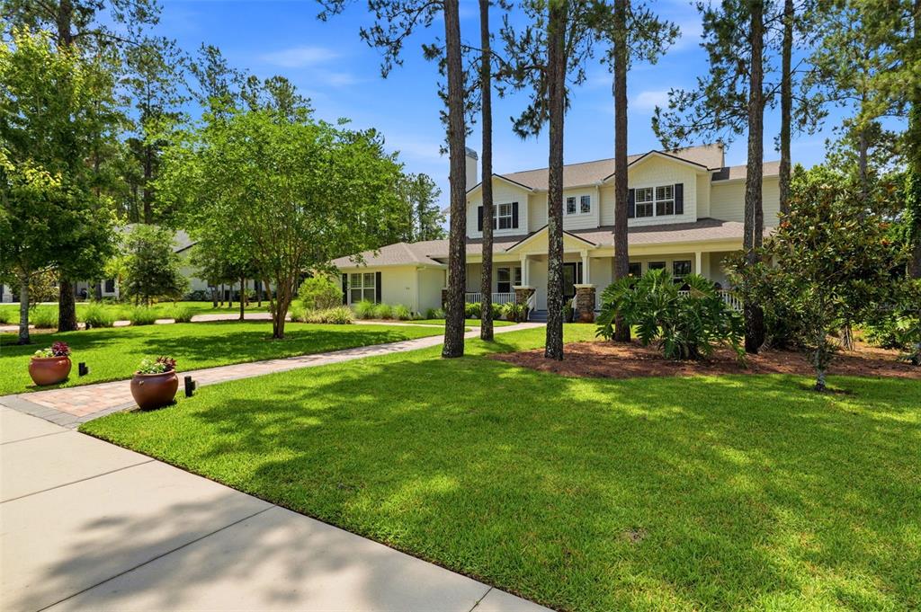 A two-story house with light siding and a front porch sits behind a grassy lawn — 5251 SUMMIT VIEW DRIVE, BROOKSVILLE, FL