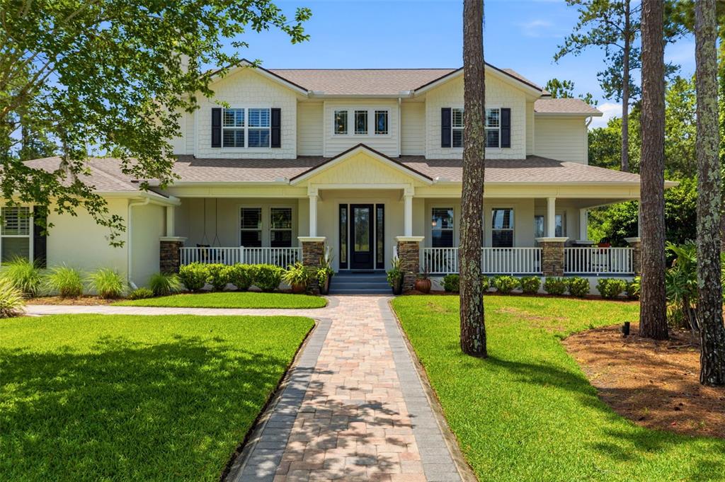 A two-story house with a front porch, stone pillars, and a paved walkway — 5251 SUMMIT VIEW DRIVE, BROOKSVILLE, FL