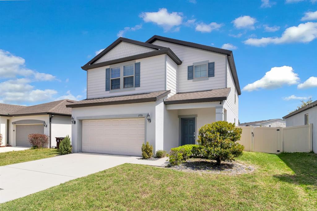 A two-story house with a white stucco facade, a two-car garage, and a front lawn — 1793 CAYMAN COVE CIRCLE, ST CLOUD, FL