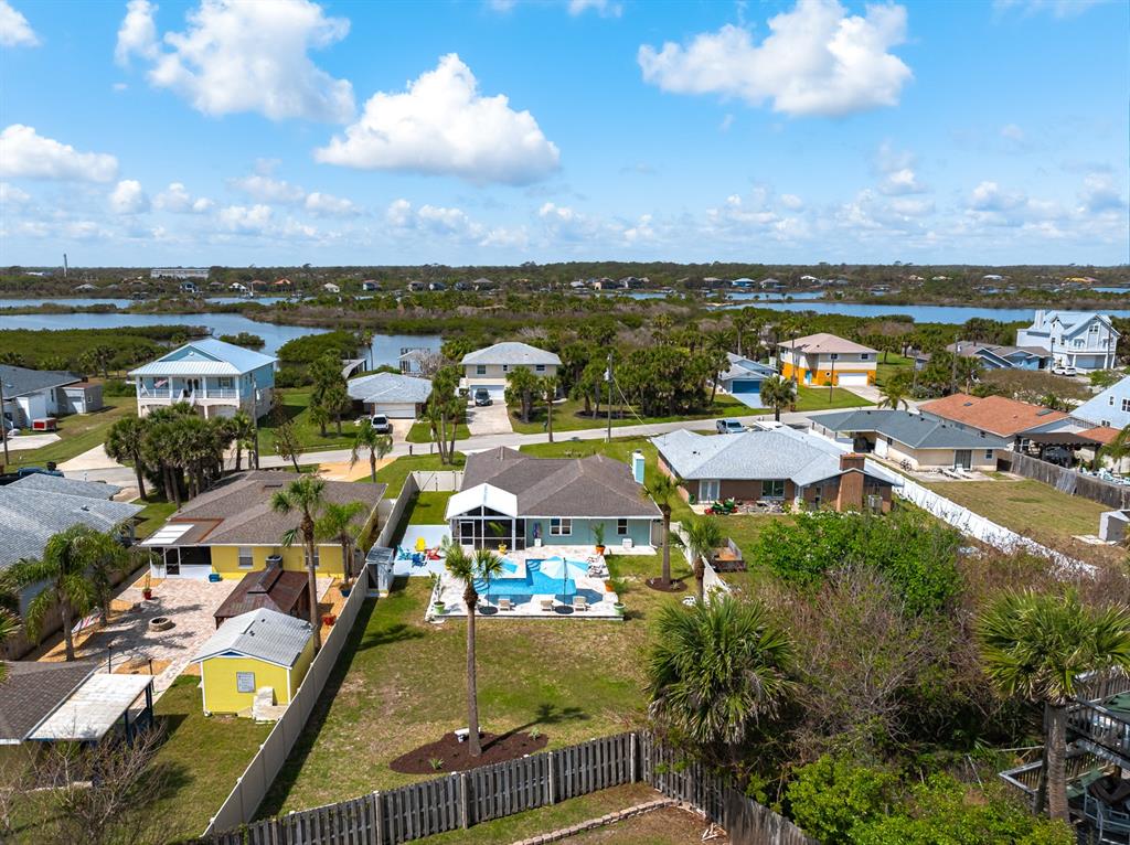 A light green single-story house features a front lawn, a paved walkway, and palm trees — 1946 N DAYTONA AVENUE, FLAGLER BEACH, FL