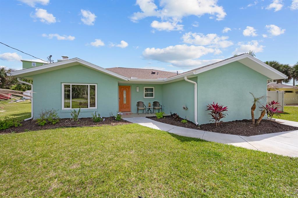 A backyard features a rectangular swimming pool, stone patio, lounge chairs, and two blue umbrellas — 1946 N DAYTONA AVENUE, FLAGLER BEACH, FL