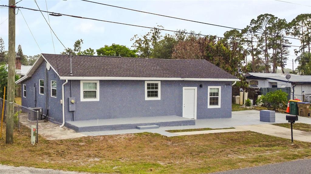 A single-story gray house with a concrete porch and driveway sits under a blue sky — 6370 BASS HIGHWAY, ST CLOUD, FL