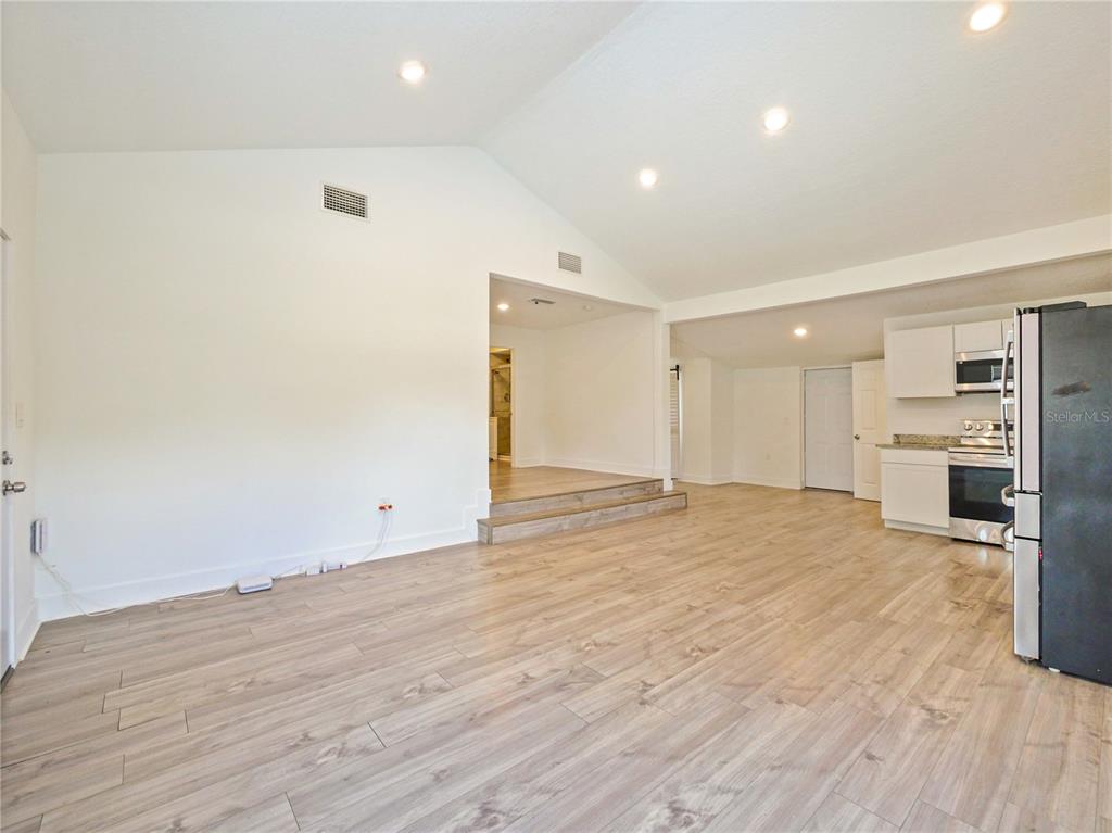An open-concept kitchen and living area features light wood-look flooring and vaulted ceilings — 6370 BASS HIGHWAY, ST CLOUD, FL