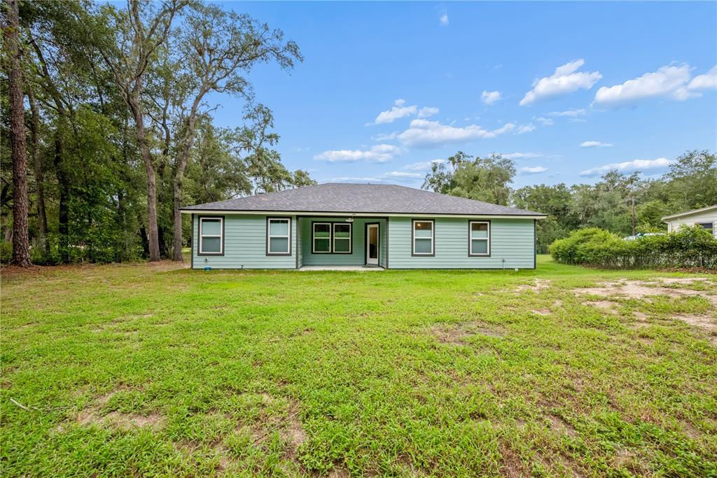 The exterior of a light green, single-story house with a dark roof and lawn — 111 BREEZEWAY AVENUE, SATSUMA, FL