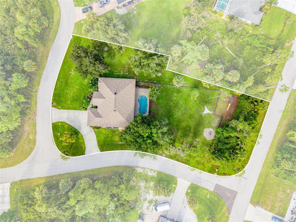 An aerial view shows a house with a pool on a large, landscaped corner lot — 1464 HALACKA ROAD, NORTH PORT, FL
