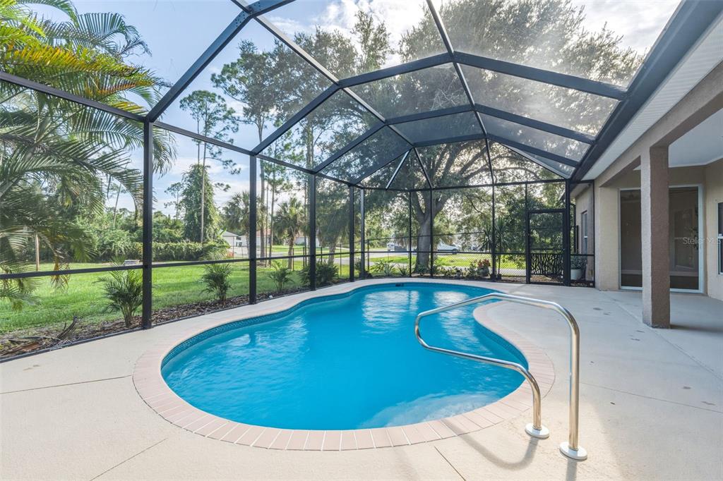 A screened-in swimming pool with a concrete deck and a metal handrail — 1464 HALACKA ROAD, NORTH PORT, FL