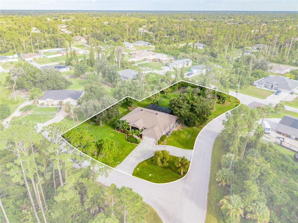 An aerial view shows a single-story house with a pool enclosure on a corner lot — 1464 HALACKA ROAD, NORTH PORT, FL