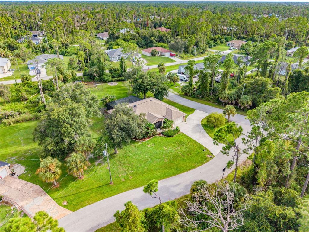 An aerial view shows a single-story house with a screened pool surrounded by dense trees — 1464 HALACKA ROAD, NORTH PORT, FL