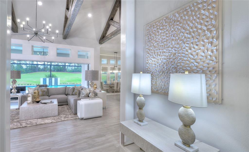 A view from a hallway into a living room with vaulted ceilings and pool views — 1009 SUDBURY LANE, ORMOND BEACH, FL