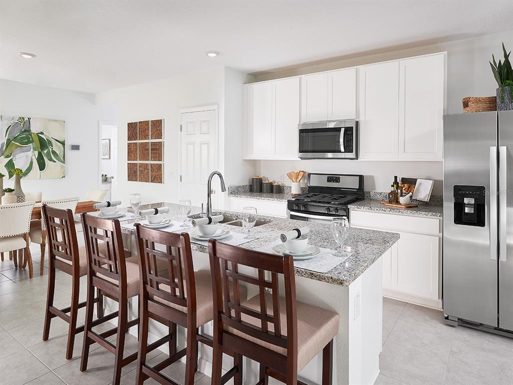 A kitchen features white cabinets, granite countertops, stainless steel appliances, and a central island — 3377 LINGER LANE, LAKE HAMILTON, FL