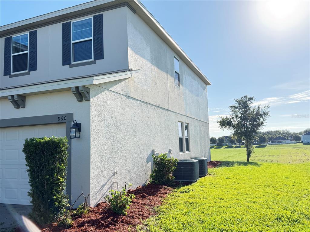 A two-story stucco house exterior features a garage, dark shutters, and two outdoor HVAC units — 860 BAY BRIDGE CIRCLE, APOPKA, FL