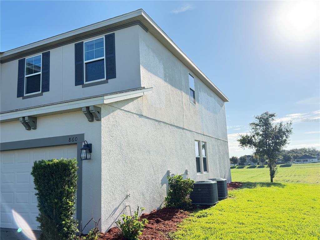 A two-story house exterior features a garage, stucco siding, and two air conditioning units — 860 BAY BRIDGE CIRCLE, APOPKA, FL