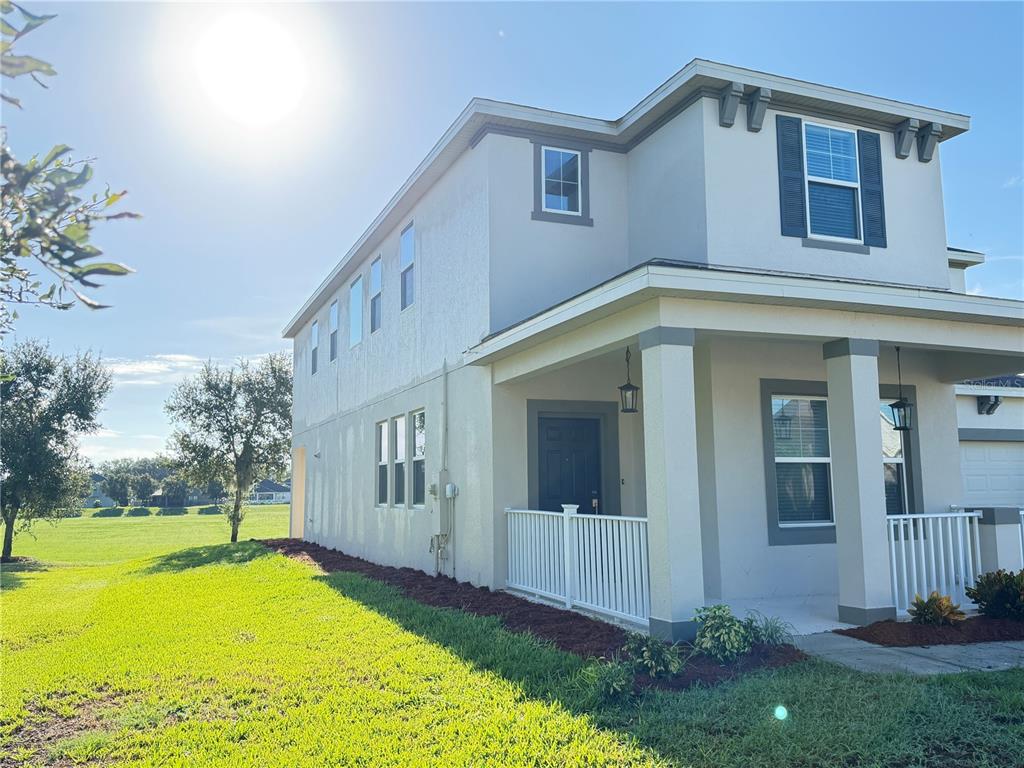 A two-story house with a covered front porch and a side yard facing a field — 860 BAY BRIDGE CIRCLE, APOPKA, FL