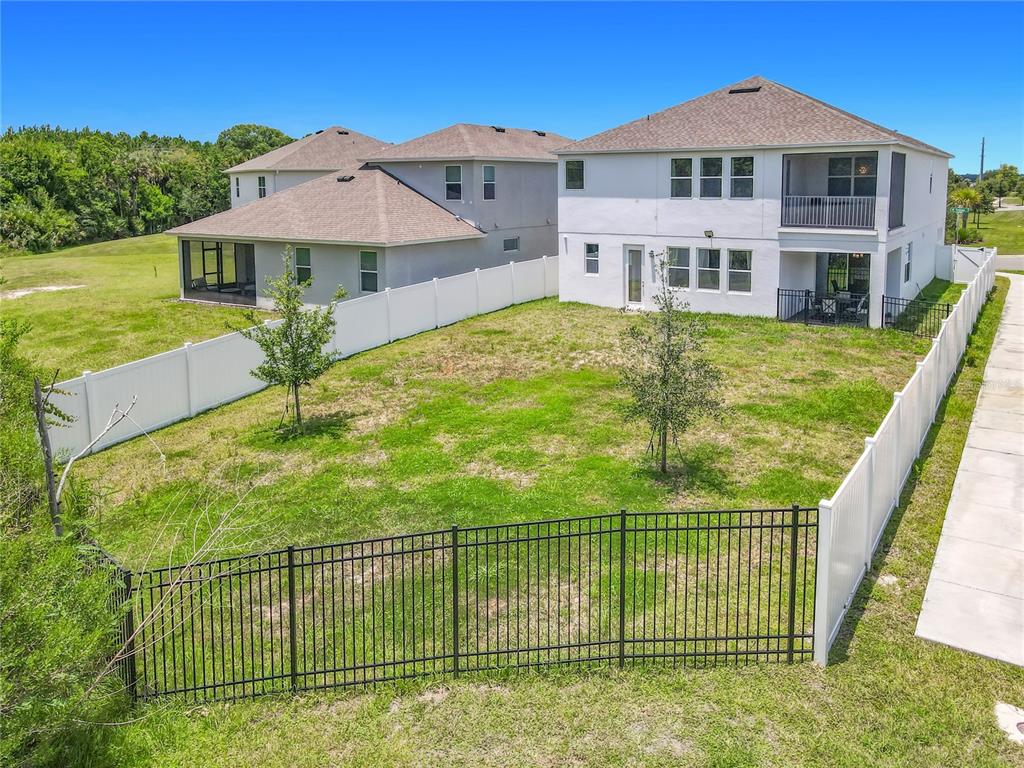 A backyard with a lawn, two small trees, and a mix of white and black fencing — 720 TREEHOUSE LOOP, DEBARY, FL
