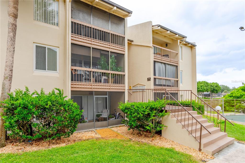 Exterior view of a multi-story apartment building with screened balconies and concrete stairs — 618 ORANGE DRIVE UNIT 216, ALTAMONTE SPRINGS, FL