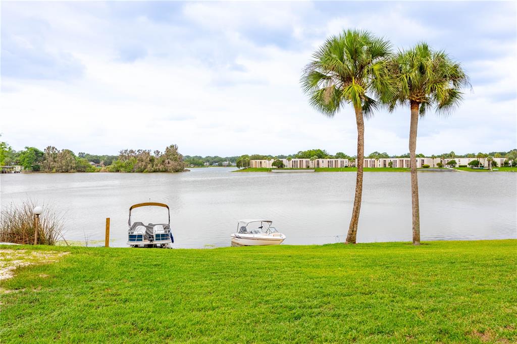 A grassy lawn overlooks a lake with two boats docked near two palm trees — 618 ORANGE DRIVE UNIT 216, ALTAMONTE SPRINGS, FL