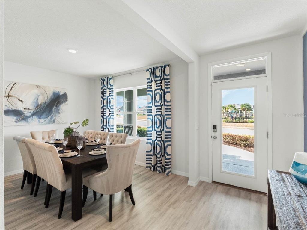 A dining room features a dark wood table, upholstered chairs, patterned curtains, and a glass-paneled door — 2482 AVEENO AVENUE, HAINES CITY, FL