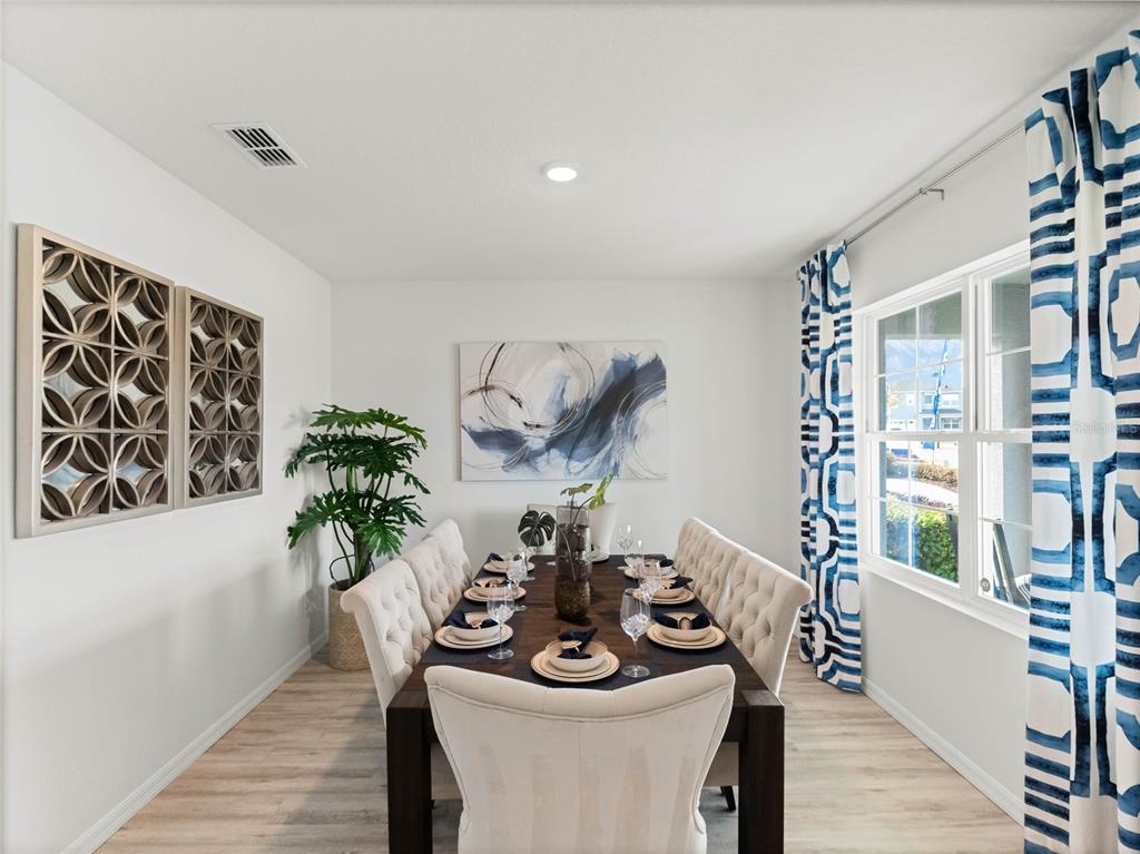 A dining room features a dark wood table, tufted chairs, patterned curtains, and wall art — 2482 AVEENO AVENUE, HAINES CITY, FL