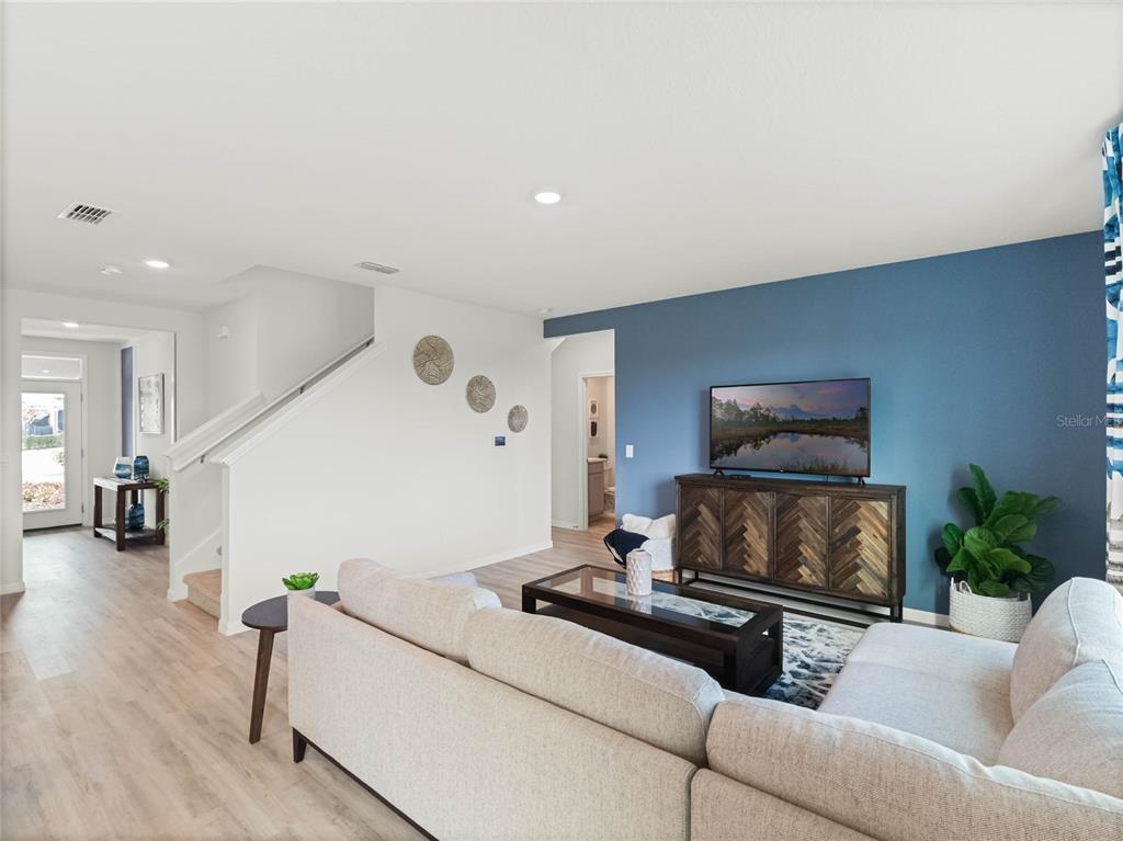 A living room features a blue accent wall, a sectional sofa, and a wooden console — 2482 AVEENO AVENUE, HAINES CITY, FL