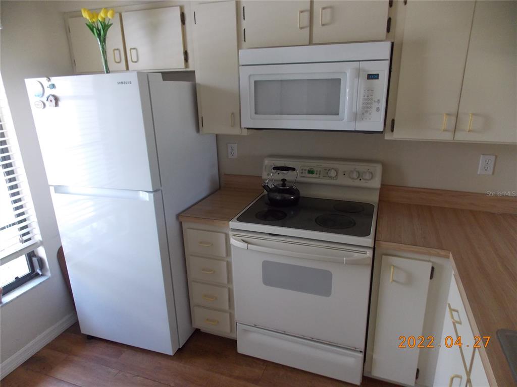 A kitchen features white appliances, light-colored cabinets, and wood-look countertops — 26267 NORTHERN CROSS ROAD UNIT 6C, PUNTA GORDA, FL