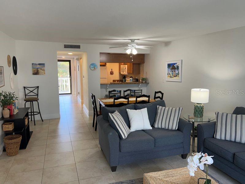 A living room with tile floors, a gray sofa, and an open kitchen with bar seating — 5350 OCEAN BEACH BOULEVARD UNIT 210, COCOA BEACH, FL