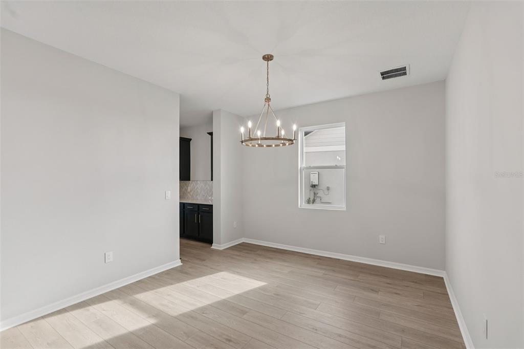A dining room with light wood-look flooring, a chandelier, and a view into a kitchen — 2909 CITRUS GROVE STREET, WIMAUMA, FL
