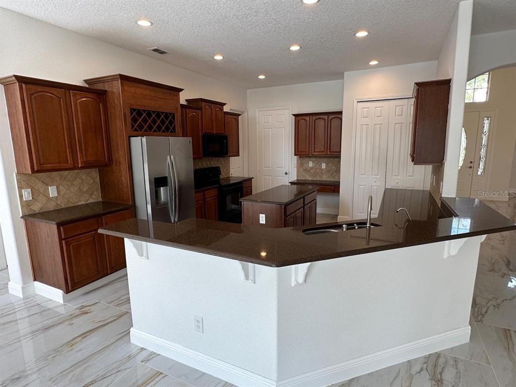 A kitchen features dark wood cabinets, brown granite countertops, and white marble-look tile flooring — 844 SPRING OAK CIRCLE, ORLANDO, FL
