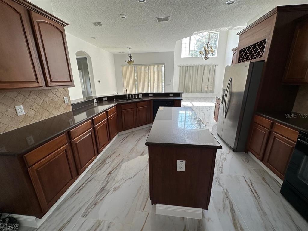 A kitchen features dark wood cabinets, granite countertops, a center island, and marble-look tile flooring — 844 SPRING OAK CIRCLE, ORLANDO, FL