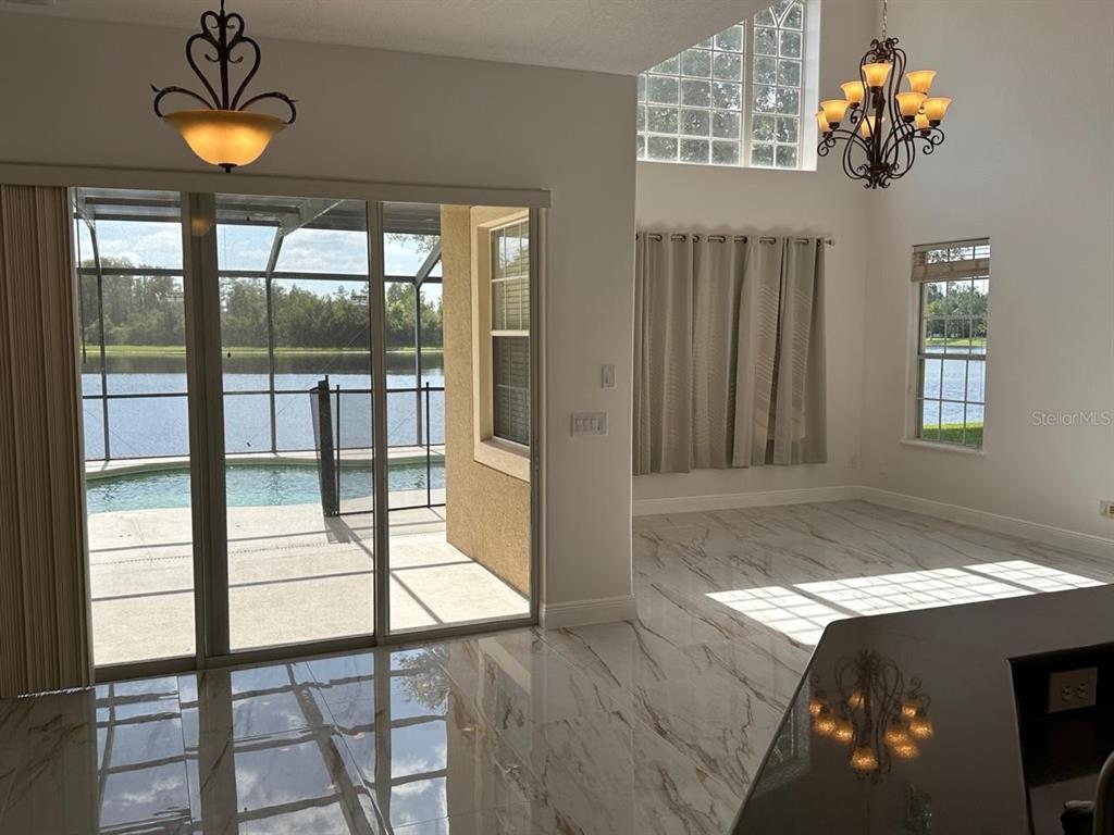 A bright room with marble-look tile floors, a chandelier, and sliding doors to a pool — 844 SPRING OAK CIRCLE, ORLANDO, FL