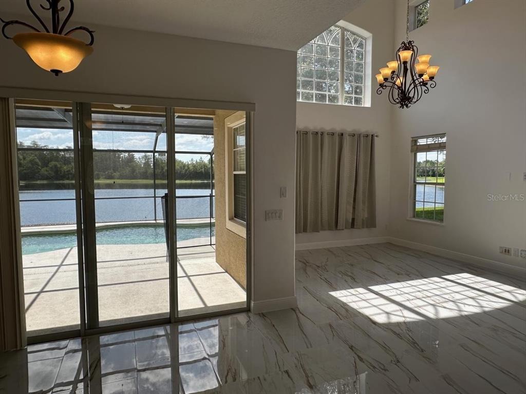 A bright room with marble-look tile floors, a chandelier, and sliding doors overlooking a pool — 844 SPRING OAK CIRCLE, ORLANDO, FL