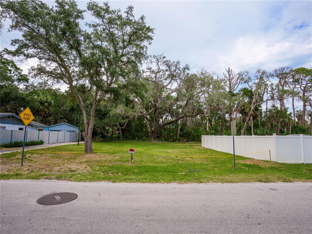 A vacant, grassy residential lot is bordered by trees and white vinyl fencing — 0 LIMESTONE, PORT RICHEY, FL