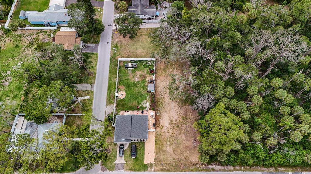 An aerial view shows a house with a fenced backyard next to a wooded lot — 0 LIMESTONE, PORT RICHEY, FL
