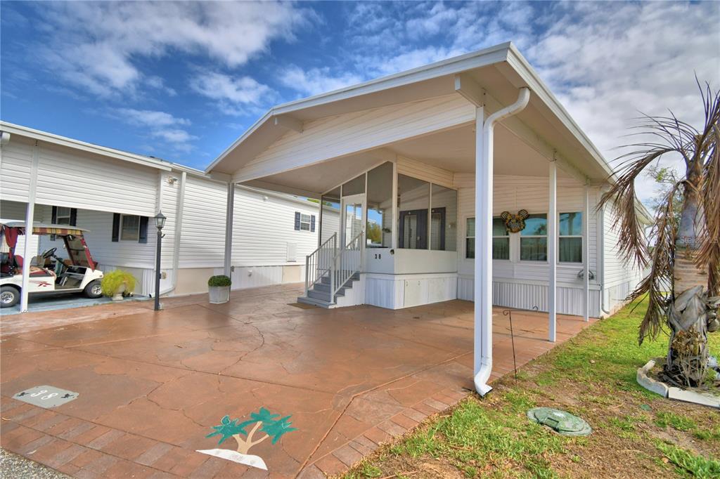 A white mobile home features a covered carport, a screened-in porch, and a painted concrete driveway — 9000 US HIGHWAY 192 UNIT 38, CLERMONT, FL